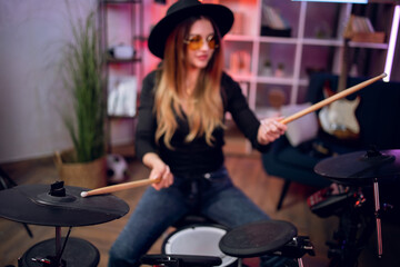 Talented female musician practising in playing electronic drums in studio. Attractive woman...