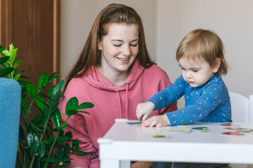 Young mother and one and a half year old girl collects puzzles. Psychomotor skills and the development of logical thinking	