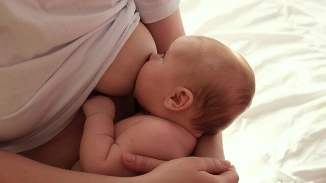 Mother breastfeeding baby at home. Mom nursing infant nurturing. Portrait of Child suckling milk from breast. Authentic shot of mother is breastfeeding her newborn baby. Close Up. Concept of maternity