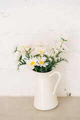 Fototapeta na wymiar bouquet of daisies flowers in a white rustic vase on the table, vertical photo.