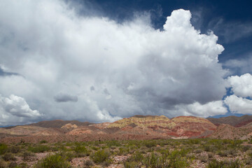 Desert landscape. View of the arid land and colorful mountains under a beautiful dramatic sky with white clouds.