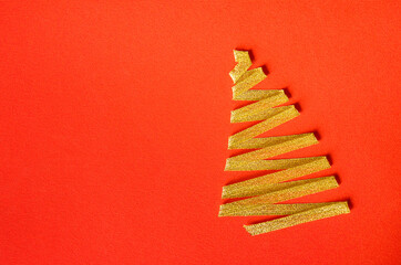Christmas tree made of gold ribbons on a bright red background. New Year and Christmas card or party invitation.