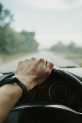 Vertical closeup shot of a hand on a steering wheel