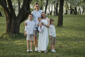 Naklejka na ściany i meble Happy family with three male children posing in park