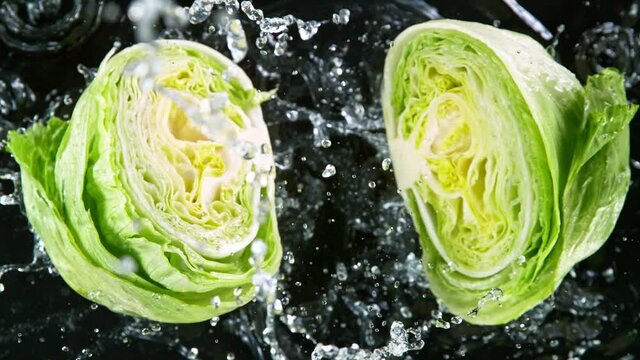 Super slow motion of falling fresh lettuce with water splashing during impact. 1000 fps.