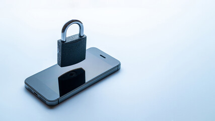 Networking security protection. Modern space grey mobile phone with padlock, key on white background. Smartphone fraud, online scam and cyber security threat.