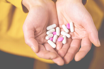 A young girl holds in her palms a handful of vitamins, supplements, drugs. Medicine and self-care.