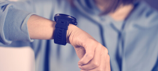 A young girl looks at a new device, a watch on her hand and keeps track of the time, hurries to a...