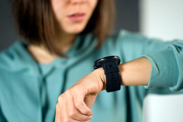 A young girl looks at a new device, a watch on her hand and keeps track of the time, hurries to a...