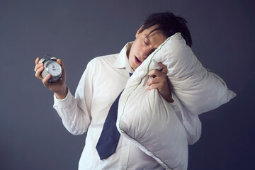 A young funny man in a white shirt and tie with disheveled hair slept through the deadline, holding...