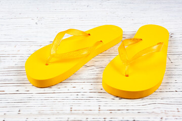 yellow rubber flip-flops on a white wooden background