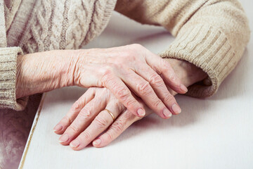 The hands of an elderly well-groomed woman in a casual sweater. The pensioner has crossed her...