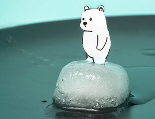 A small cute polar bear stands on a miniature piece of ice, drawn and made of paper. Global...
