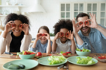 Portrait of happy multiethnic family with little diverse daughters have fun cook in home kitchen together. Smiling multiracial mom and dad preparing food with ethnic children. Diversity concept.