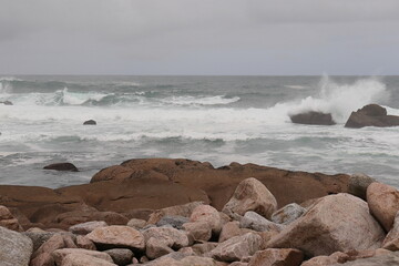 Image of waves breking against some rocks on the beach of Camelle, Galicia, Spain.