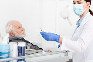 senior man having teeth treatment by dentist in latex gloves in dental clinic.