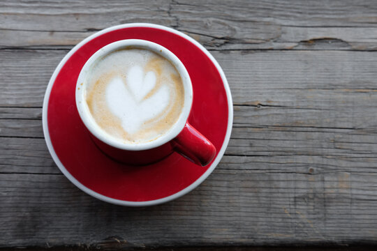 Top View Of A Red Mug With A Cappuccino On A Wooden Surface