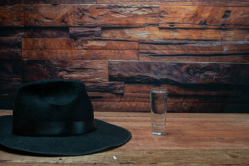 black fedora hat next to Silver Tequila Shot on old planks. travel