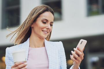 Adult attractive woman with smartphone walking in the city