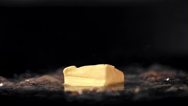 Super slow motion a piece of butter in a frying pan melts with hot steam. On a black background.Filmed on a high-speed camera at 1000 fps. High quality FullHD footage