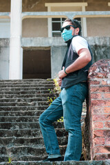 Hombre joven posando en gradas de edificio abandonado con mascarilla