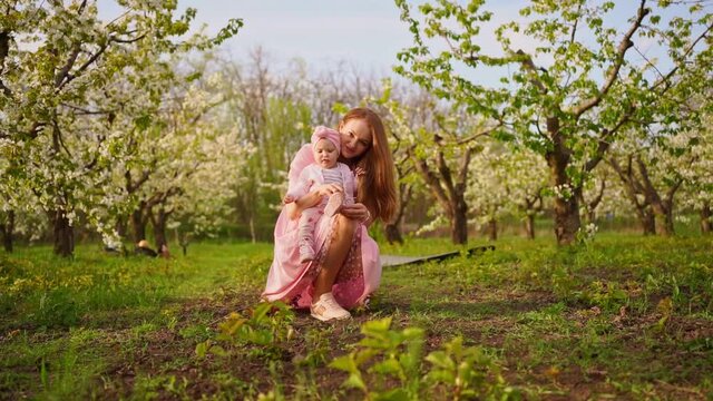 Mother tying shoelaces baby, sit in the flowering garden. cleft lip in babies.
