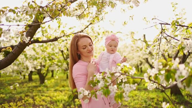 mother with baby in arms in flowering garden. surgery for child with cleft lip.