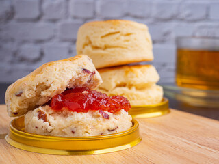 Traditional English style scones delicious freshly baked homemade with strawberry jam on a plate placed on wooden cutting board and teacup. Top view with copy space for text