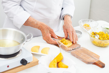 Senior woman frying a traditional dish from el Valle del Cauca in Colombia called empanada