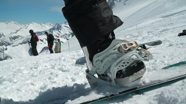 Snowboarder strapping in. Closing snowboard bindings.