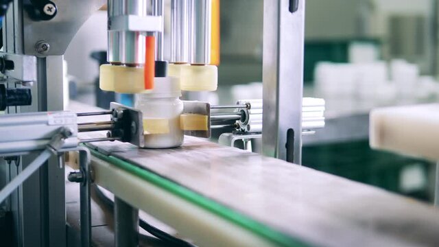 Plastic tubs are getting closed by a mechanized conveyor