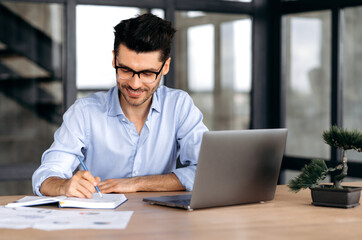 Concentrated satisfied successful caucasian businessman, freelancer or broker wearing glasses,...