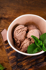 Balls of homemade chocolate ice cream with mint in a bowl close up vertical photo with soft focus