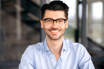 Close up portrait of handsome confident successful young caucasian man wearing glasses, wearing...