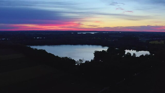 Wonderful aerial morning view over the Feringasee in Unterfoehring with a vibrant red colored sunrise. Wonderful start into a new day.