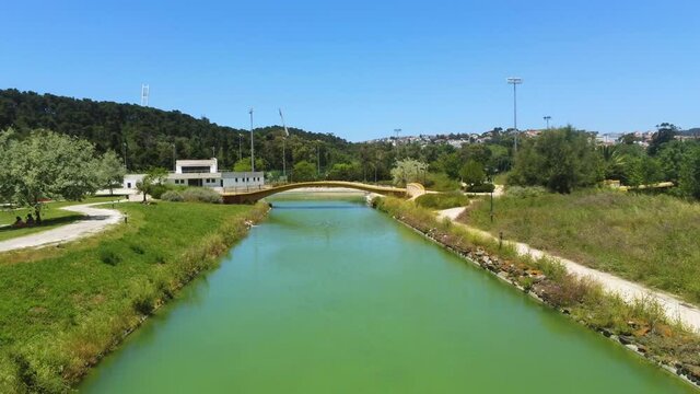 Aerial view low over green water in the Nautical Activities Track, in Lisbon - rising, pull back, drone shot