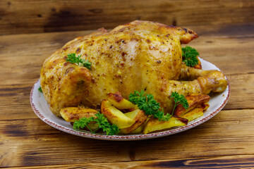 Baked whole chicken with potato on a wooden table