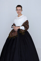 A Victorian woman wearing a white Garibaldi blouse and black skirt  with a paisley shawl