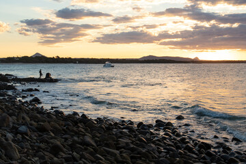 Fototapeta premium Silhouette of Man Standing on Rocks Looking at Sea Sunset in Australia.Traveler Concept