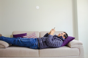 young man watching television and chatting form the cellphone during covid pandemic time