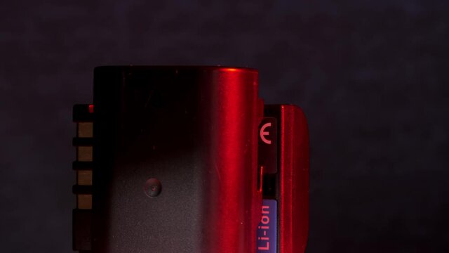 Remote controller alkaline accumulators rotate reflecting bright red electric light against grey wall at darkness closeup. Concept power supply