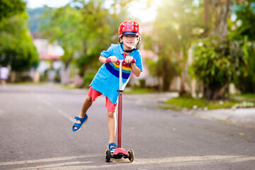 Little boy riding scooter. Kids ride kick board.