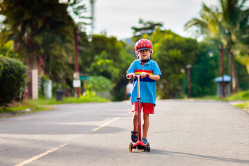 Little boy riding scooter. Kids ride kick board.