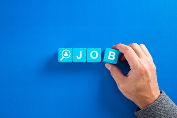 The word job on wooden cubes with on blue background. Searching for a job, employment, recruitment or career concept.