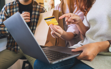 Group of young people using laptop and credit card for shopping online together