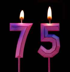 Burning birthday candles isolated on black background, number 75