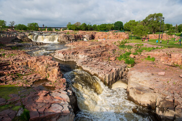 Fototapeta na wymiar The Falls of the Big Sioux River tumble a total of 100 feet through many little cascades and waterfalls. The Sioux Quartzite gives the whole area this pinkish red color.