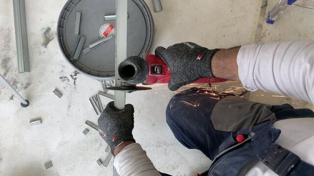 Cutting metal profile with a grinder during repair work. Lots of friction sparks. Professional builder worker cuts metal profile