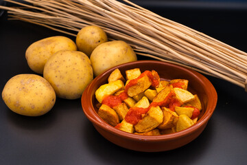 Fotografie von einer Schüssel gefüllt mit spanischen Patatas Bravas, Kartoffelecken mit einer scharfen Soße.