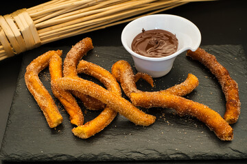 Fotografie von Churros mit Schokoladensoße auf einer Schieferplatte.